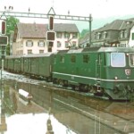 La locomotiva Re 4/4 II 11217 e il suo treno passeggeri provocano onde che si diffondono a cuneo a lato del treno. 01.08.1987 Foto: E. Meier