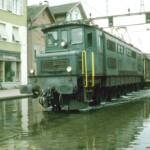 Ae 4/7 11019 with its long freight train also gets its feet or rather wheels wet. Here, too, you can nicely see how the generated waves stir up the mirror-smooth surface of the water. August 01, 1987 Photo: E. Meier