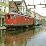 Infine, una suggestiva immagine della Re 4/4 I 10035 verniciata di rosso con un treno passeggeri. Anche in qesto caso il carrello della prima vettura del treno è fumante, questa volta una B del tipo leggera a porte semicentrali. 01.08.1987 Foto: E. Meier